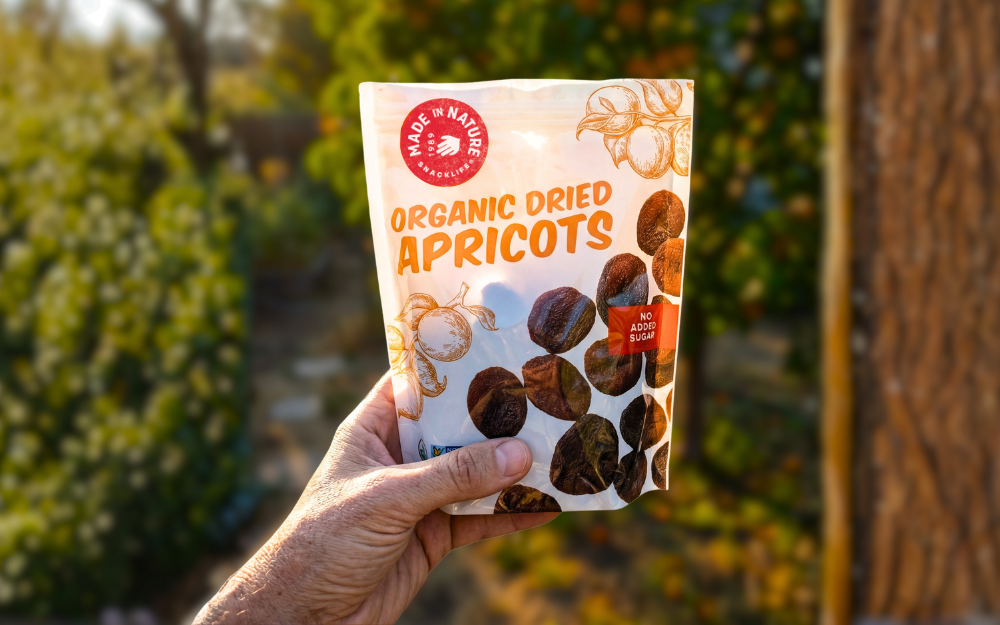 An apricot package with a blurry orchard background.