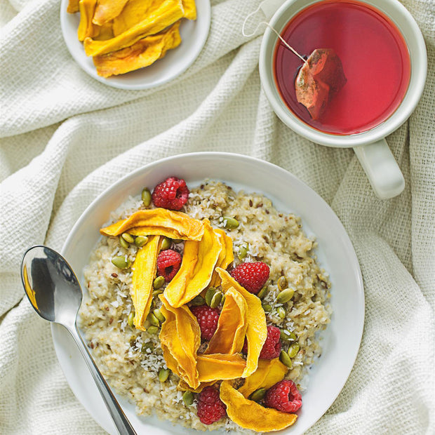 Oatmeal with fruit and a cup of tea on a light fabric background