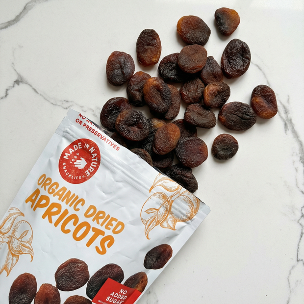 Organic dried apricots with a package labeled 'Made in Nature Organic Dried Apricots' on a marble surface.